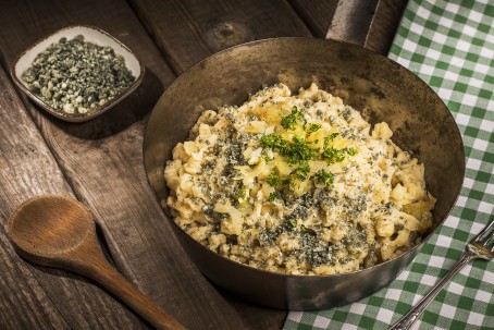 Ennstaler Käsespätzle - In einer schwarzen Schüssel sind die deftigen Käsespätzle amgerichtet. Als Deko ist auf der Portion gehackte Petersilie und fein geschnittener Zwiebel gestreut. (Foto: VrK/Alexander Stiegler - Nicht zur freien Verwendung)