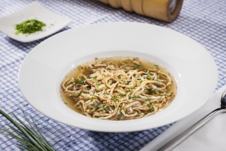 Frittatensuppe - In einem großen tiefen weißen Suppenteller ist eine Portion Rindssuppe mit Frittaten angerichtet. Darüber ist frischer Schnittlauch gestreut. (Foto: VrK/Alexander Stiegler - Nicht zur freien Verwendung)