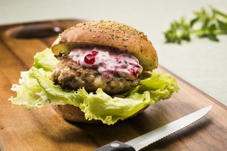 Rehburger - Auf einem braunen Holztisch liegt ein aufgeschnittenes Burgerweckerl mit einem Salatblatt auf dem ein saftig gebratener Burger, garniert mit einer weiß/roten Sauce (Foto: VrK/Alexander Stiegler - Nicht zur freien Verwendung)