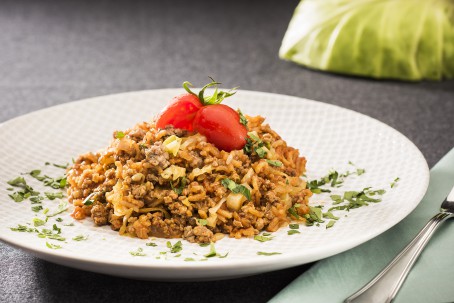 Reispfanne - Auf einem weißen Teller liegt eine Portion gelb/braun gefärbter Reis, garniert mit zwei roten Tomaten und Kräutern. Danebenliegt eine Gabel und eine Serviette (Foto: VrK/Alexander Stiegler - Nicht  zur freien Verwendung)