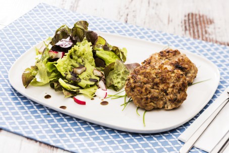 Topfen-Fleisch-Laibchen - Auf einem weißen Teller liegen zwei knusprig gebratene Laibchen, daneben grüner Blattsalat, garniert mit Kürbiskernöl und Radieschen (Foto: VrK/Alexander Stiegler - Nicht zur freien Verwendung)