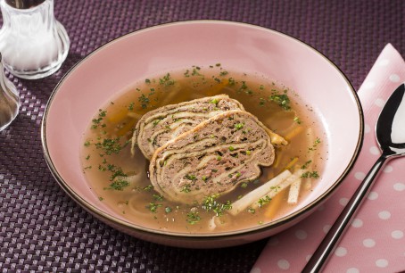 Leberroulade - In einem rosa Teller liegen zwei Stück der Leberroulade, ganiert mti Kräutern. In der Suppe befindet sich noch Suppengemüse (Foto: VrK/Alexander Stiegler - Nicht zur freien Verwendung)