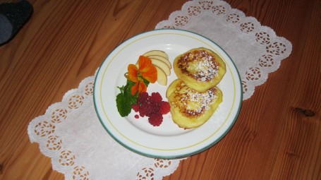 Flotte Topferl mit Frucht - Auf einem runden Teller befinden sich zwei goldbraun angebratene Topfenlaibchen mit Äpfeln und Himbeeren garniert. (Foto: Regina Putz - Nicht zur freien Verwendung)