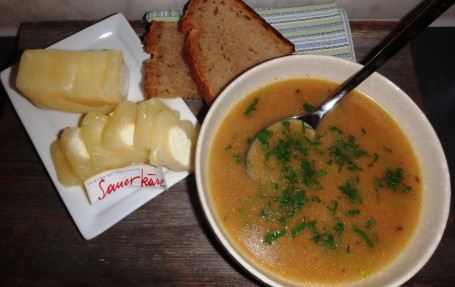 Einbrennsuppe mit Sauerkäse - Auf dem Bild ist die Einbrennsuppe garniert mit gehackter Petersilie zu sehen. Auf einem Teller sind der aufgeschnittene Sauerkäse und zwei Bauernbrotstücke. (Foto: Sigrid Gasser - Nicht zur freien Verwendung)