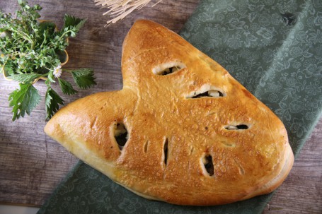 Brotblatt mit Schafkäse, Kräuter und Schinken gefüllt - Auf dem Bild befindet sich mittig das Brotblatt auf einem dunkelgrünen Tuch. Daneben ist noch ein grüner Blumenstock. (Foto: Heidegger/LK Niederösterreich - Nicht zur freien Verwendung)