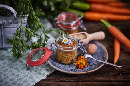 Karottenkuchen im Glas - Auf einem blau melierten Teller befindet sich im Glas der Karottenkuchen.  Nüsse, Karotten und Kräuter dienen einer wunderschönen Verzierung. (Foto: VrK/Franz Gleiß - Nicht zur freien Verwendung)