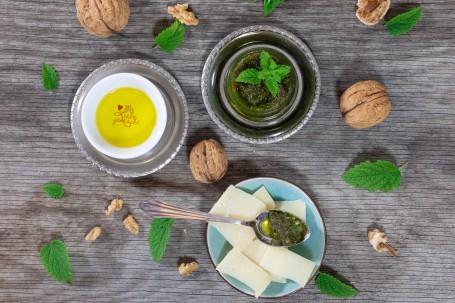 Zitronenmelissen-Pesto - 1 graues Schälchen mit grünem Pesto, garniert mit Zitronenmelisse, ein weißes Schälchen mit gelben Inhalt und der Aufschrift (Foto: VrK/Achim Mandler Photography - Nicht zur freien Verwendung)