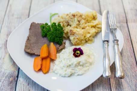 Gekochtes Rindfleisch mit Gerösteten Erdäpfel und Apfelkren - Auf einem weißen Teller liegt ein Stück mageres Rindfleisch, garniert mit Petersilie und kleinen halbierten Erdäpfel, daneben der weiße Semmelkren und die hellgelb gerösteten Erdäpfel, vermischt mit Zwiebel (Foto: VrK/Achim Mandler Photography - Nicht zur freien Verwendung)