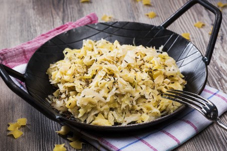 Krautfleckerl - Auf einem Geschirrtuch steht eine kleine schwarze Pfanne. Darin sind Fleckerl gemeinsam mit Kraut, Zwiebel und Kümmel zu sehen. (Foto: VrK/Alexander Stiegler - Nicht zur freien Verwendung)