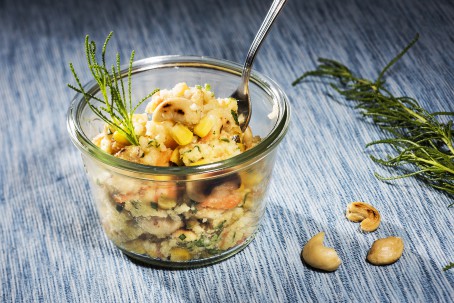 Bunter Hirsesalat mit Maroni - In einem kleinen Dessertglas ist der bunte Hirsesalat angerichtet. Einzelne Cashewnüsse sind zu erkennen. Eine gabel steckt im Salat. Neben dem Glas liegen 3 Cashewnüsse als Deko. (Foto: VrK/Alexander Stiegler - Nicht zur freien Verwendung)